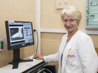 Lekarka w białym kitlu prezentuje zdjęcie rentgenowskie stopy